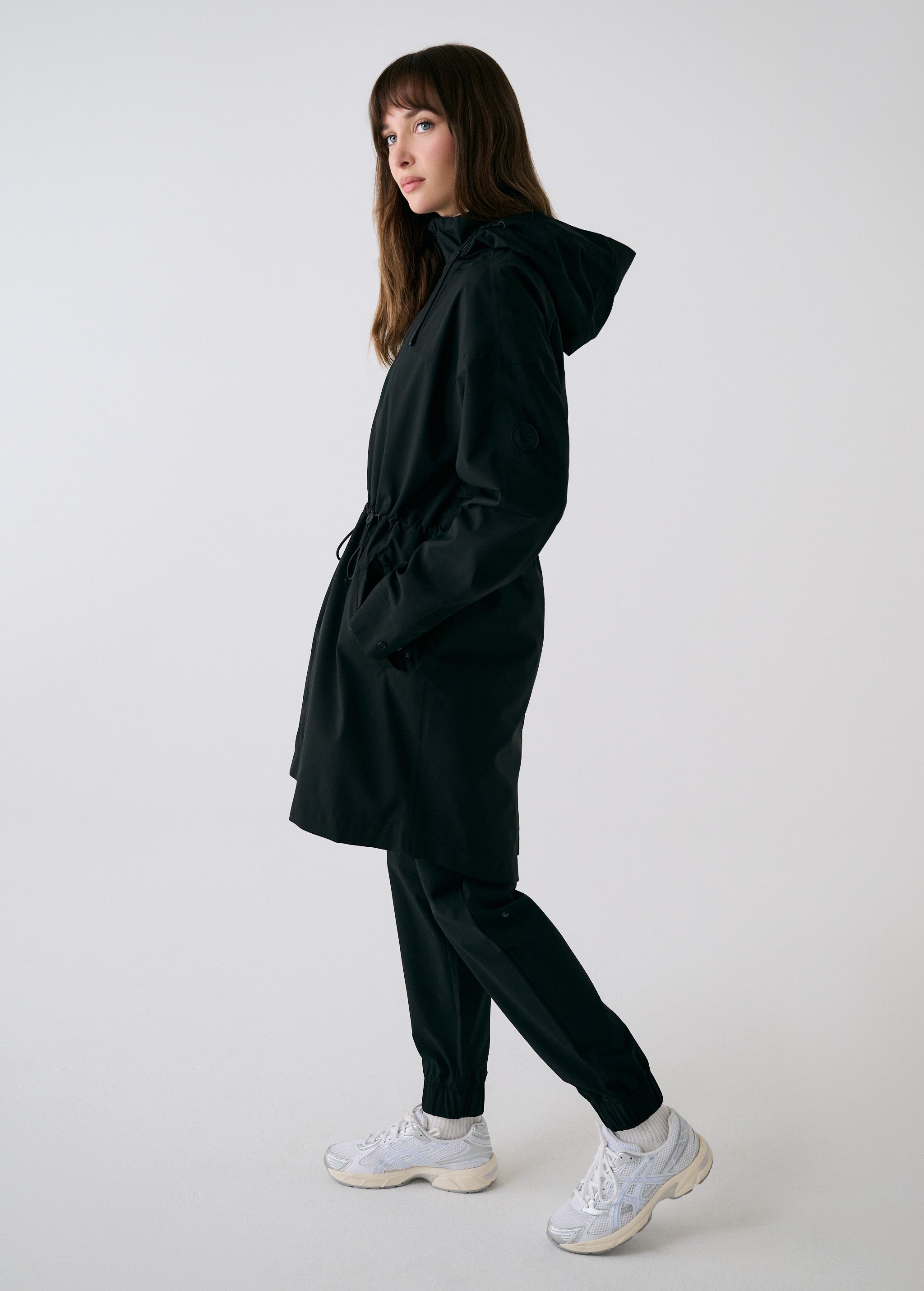 Lolë Piper 2.0 rain jacket in black, full side profile with hood down showing the mid-thigh length
